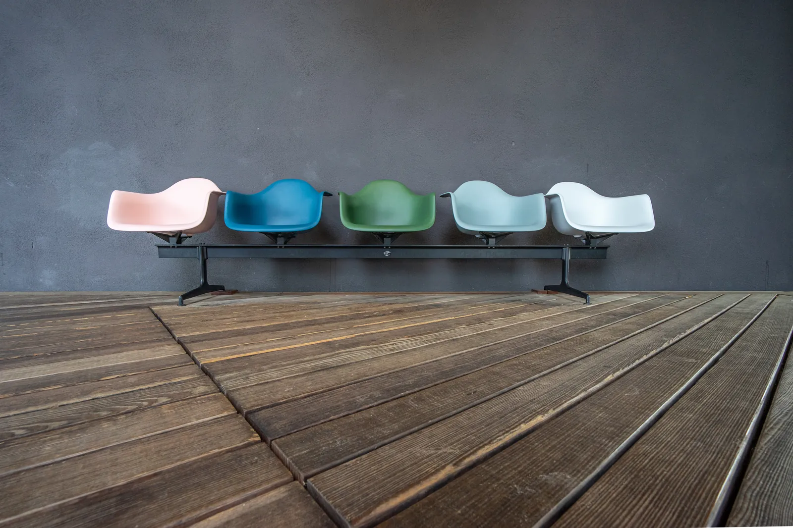 Eames Plastic Armchair RE en Vitra Campus, Weil am Rhein (febrero 2024): silla apilable color crema sobre suelo de hormigón, paredes industriales blancas al fondo
