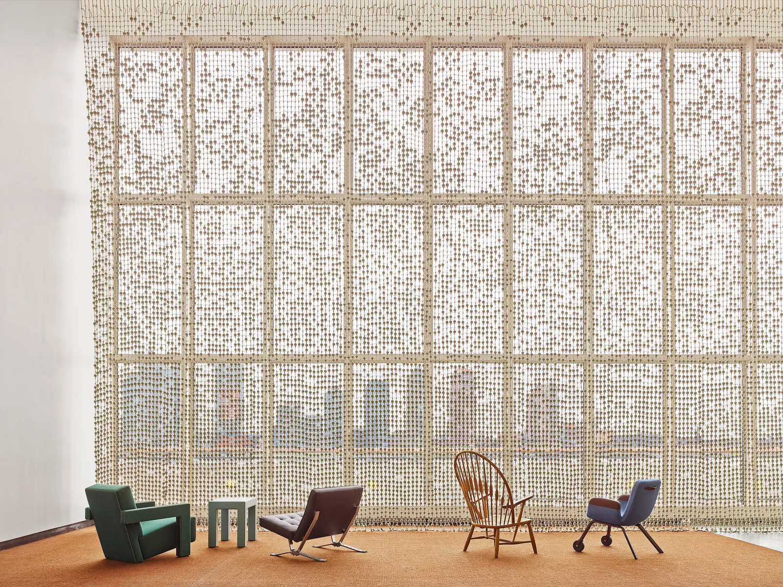 UN Delegates Lounge en Nueva York rediseñado por Hella Jongerius: cortina Knots & Beads de cuentas trenzadas cubriendo la pared del fondo, sillas históricas (Rietveld verde, Wegner, butaca cuero, sillón azul) sobre alfombra terracota