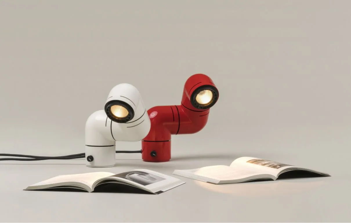 Lámparas Tatu de André Ricard (1972) en versiones blanca y roja, con dos libros abiertos sobre fondo crema, parte de la exposición Diseño en uso