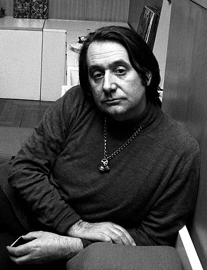 Retrato de Ettore Sottsass en 1969, jersey cuello alto oscuro, mirada introspectiva, estudio doméstico al fondo