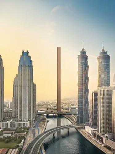 Render de Muraba Veil en el skyline de Dubai: torre estrechísima vertical color terracota destacando entre rascacielos clásicos de cristal y acero, río en primer plano